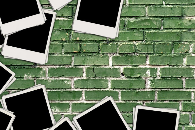 Blank photos on scattered on a green brick background